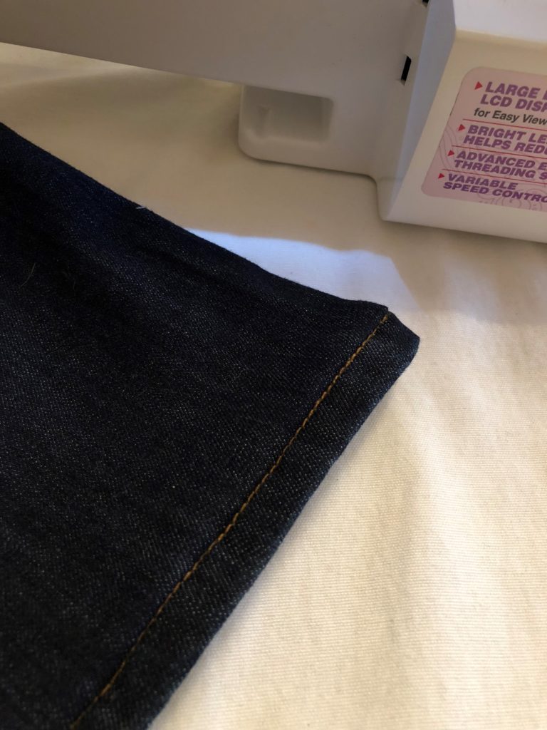 Pant leg of a pair of jeans with a finished hem.