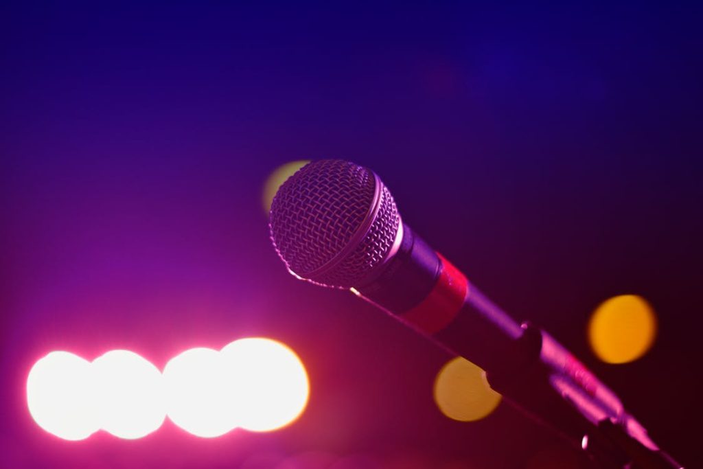 A close up of a microphone against blurred stage lighting.