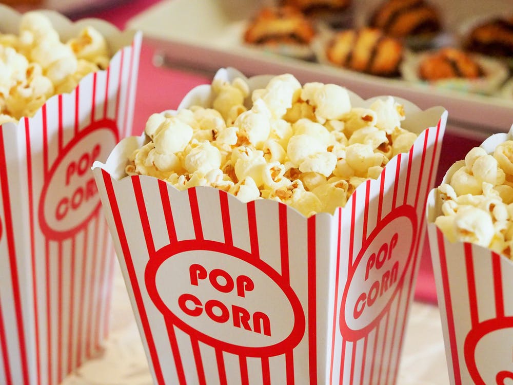 A red and white striped container filled with fluffy, yellow, buttery popcorn. 