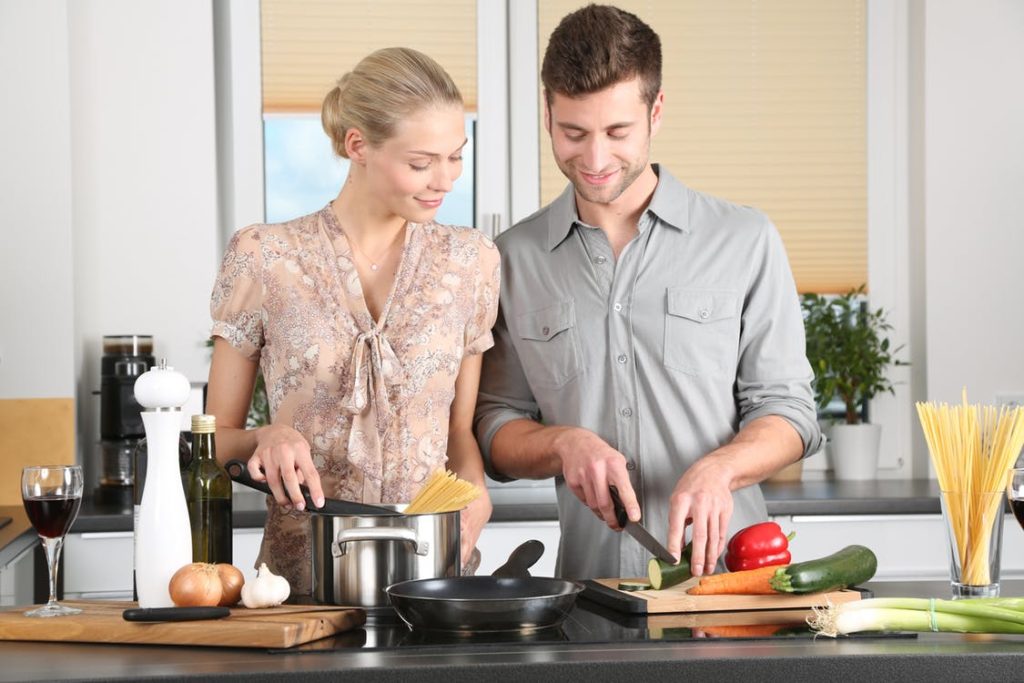 A man and a women couple cooking together for Valentine's day in a kitchen.