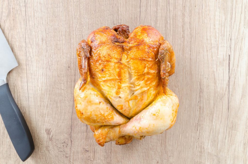 A cooked, whole chicken lays on a cutting board next to a knife. Instant pot recipes. 