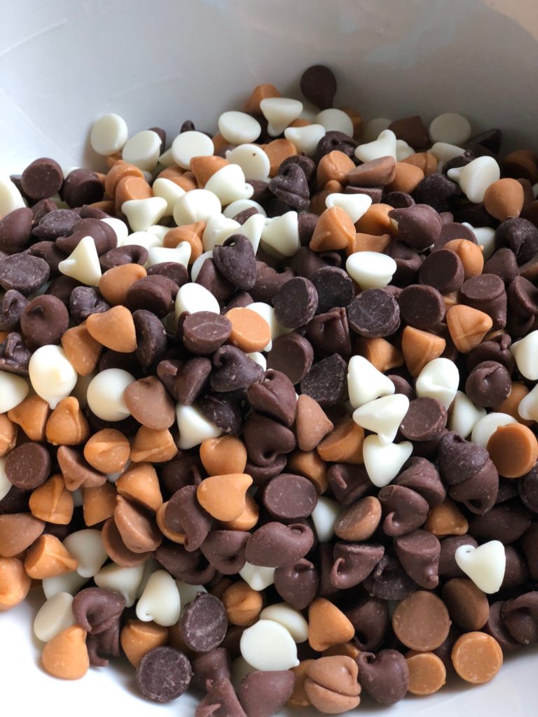 Five different types of chips in a bowl, with colors ranging from white to orange to dark brown chips for the best chocolate chip cookies. 