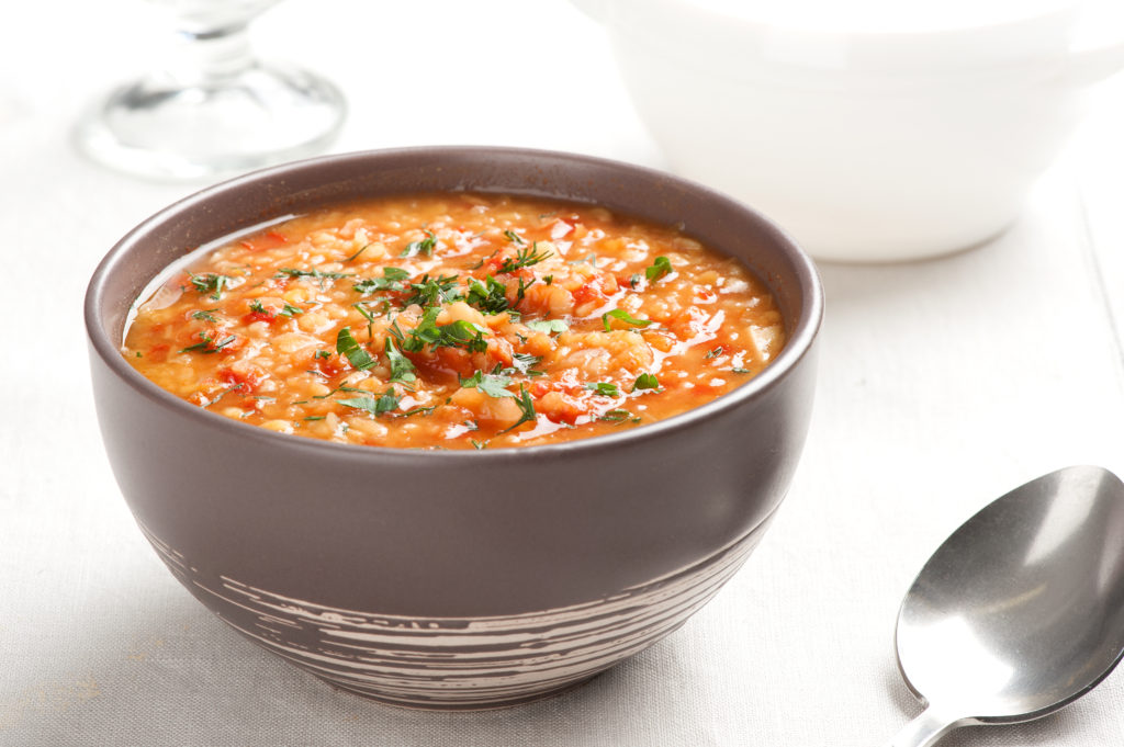 Weight Watchers Slow Cooker Stuffed Pepper Soups sits on top of a table in a gray bowl next to a spoon.