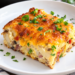 A serving of 1 point mashed potato bake topped with scallions sits on top of a white plate.