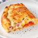 A baked ham and pepperoni calzone sits on top of a white plate.