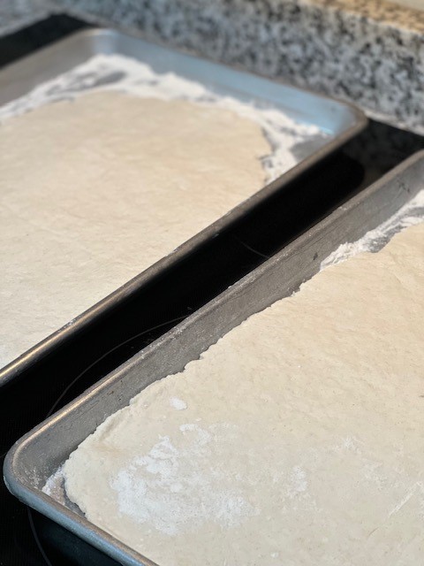 Two sheets of rolled dough sit on baking pans. 