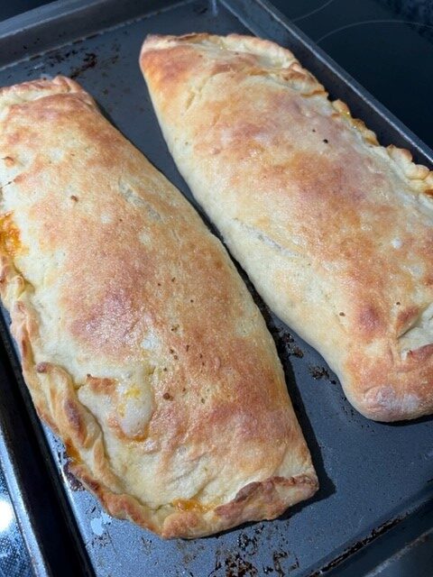 Fully baked calzones sit on baking sheet to cool. 