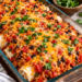 A pan of baked burritos sits on a table.