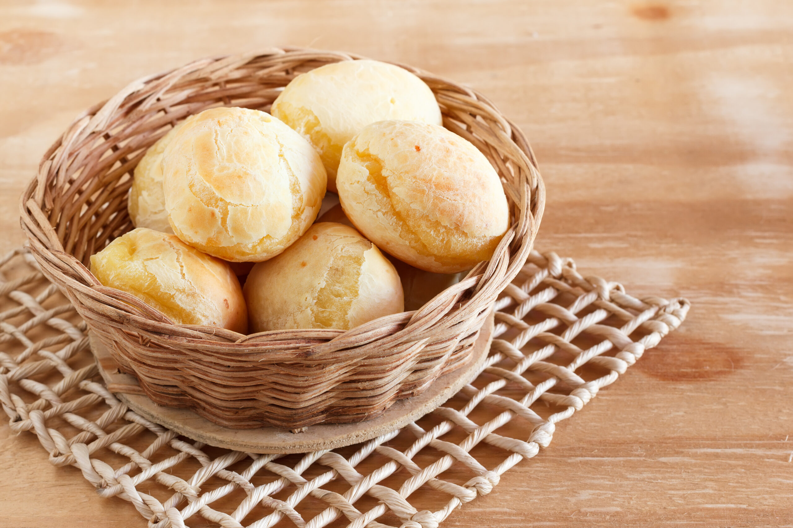 A basket of rolls sits on top of a cooling rack on a table.