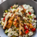 A Greek chicken bowl sits on a table looking down on it.