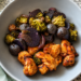 Crispy air fryer chicken and roasted broccoli, mushrooms, onions, and purple potatoes in a grey bowl on a counter.
