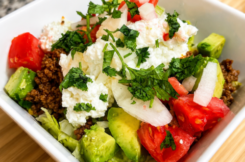 A taco bowl sits on top of a cutting board on a counter.